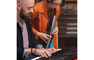 musician playing Roland Aerophone Pro AE-30 in recording studio alongside keyboardist playing Roland Fantom workstation keyboard