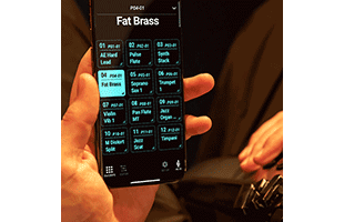 point-of-view image of musician playing Roland Aerophone Pro AE-30 while holding smartphone running Roland companion app