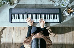 view from above of musician playing Casio Casiotone CT-S1 - Black on dining room table