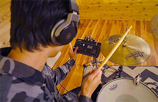 rear closeup view of drummer wearing headphones and interacting with Yamaha EAD10 module with drum kit in background