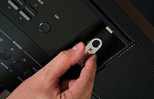 close-up image of hand inserting USB flash drive into USB-to-device port on top of Kawai ES520 digital piano