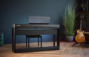 Kawai ES920 digital piano sitting on small stage with guitar and plant