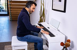 musician wearing headphones playing Roland FP-60x in living room