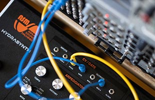 detail image of Hydrasynth CV/gate patch points with patch cables connecting to eurorack modular synthesizer in background