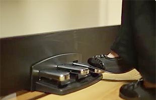 close-up side image of piano player's foot pressing sustain pedal on Korg LP-380U