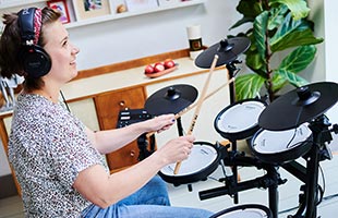 side view of drummer playing Roland TD-07DMK in living room