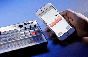 hand holding smartphone running Korg AudioPocket app next to Korg Volca Sample 2